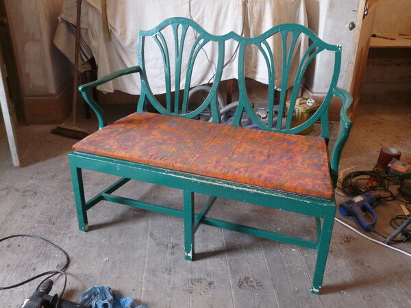 Hepplewhite-style double settee stripped bare outdoors, paint peeling, cane seat panel removed — before restoration