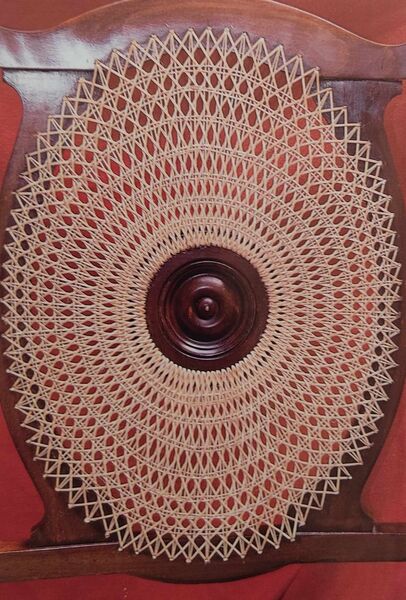 Circular medallion chair back with freshly completed sunburst spoke caning radiating from a central boss — after restoration